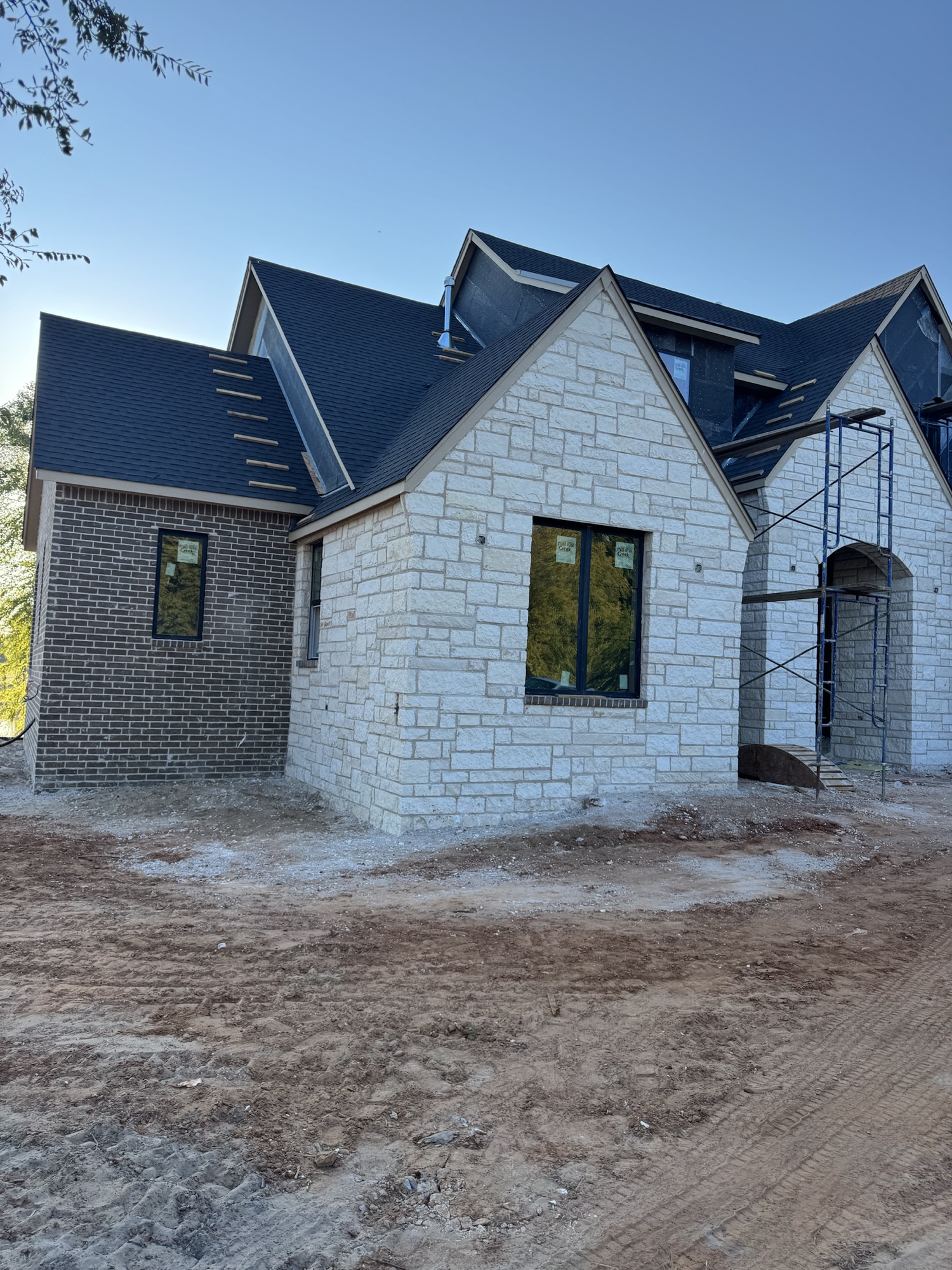 Cozort Custom Homes project under construction in Tulsa featuring dark brick and light natural stone